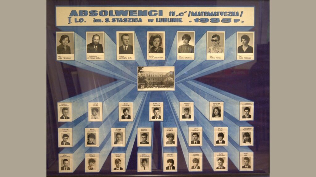 Tło w odcieniach niebieskiego z promieniście rozchodzącymi się pasami od centralnie umieszczonego zdjęcia budynku szkoły. Na górze napis: „Absolwenci IV c / Matematyczna / I LO im. S. Staszica w Lublinie – 1985 r.” W górnym rzędzie – zdjęcia nauczycieli, dyrektora i wychowawców. W dolnej części – 26 czarno-białych zdjęć uczniów w dwóch rzędach, każdy portret podpisany. Tło dla zdjęć to błękitne pasy na granatowym tle.