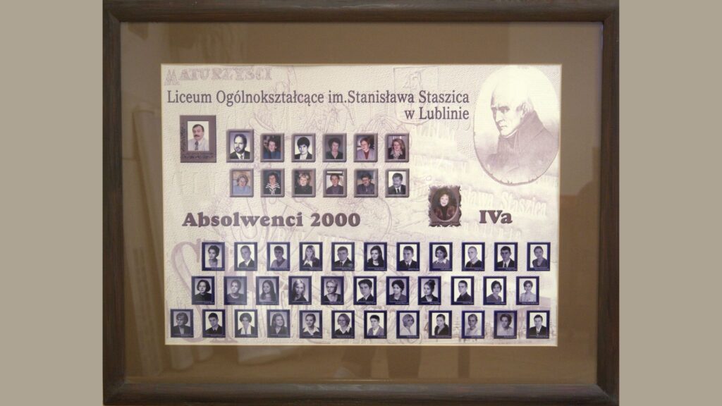 Plansza w ramie drewnianej. Dominujące kolory to odcienie beżu i sepii. W lewym górnym rogu tekst: „Liceum Ogólnokształcące im. Stanisława Staszica w Lublinie”. Z prawej strony grafika z wizerunkiem Stanisława Staszica. Góra planszy: zdjęcia nauczycieli i wychowawców, w ramkach. Środek: napis „Absolwenci 2000 IVa”, obok ozdobna fotografia wychowawczyni. Dół: dwa rzędy portretów uczniów (czarno-białe, w fioletowych ramkach), podpisane imieniem i nazwiskiem.