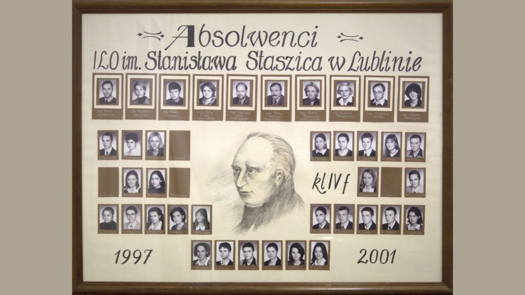 Plansza beżowa z brązowymi ramkami wokół zdjęć. Centralnie umieszczony szkicowany portret Stanisława Staszica, który dominuje nad kompozycją. Góra – zdjęcia kadry. Po bokach i na dole – czarno-białe zdjęcia uczniów z podpisami, symetrycznie rozmieszczone wokół rysunku.