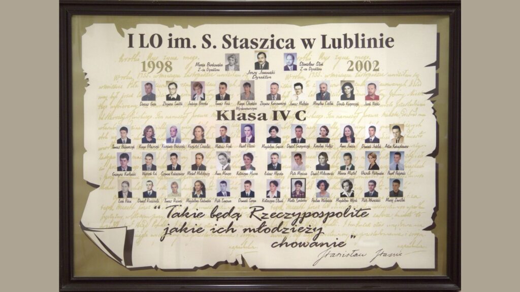 Tło przypomina stary zwój pergaminu. Na górze – napisy: „I LO im. S. Staszica w Lublinie” Po lewej – rok „1998”, po prawej – „2002”. W centrum: zdjęcia dyrekcji, nauczycieli i wychowawców – kolorowe. Niżej – 6 rzędów portretów uczniów – niektóre kolorowe, inne czarno-białe. Łącznie ponad 40 osób. Na dole cytat wypisany kaligrafią: „Takie będą Rzeczypospolite, jakie ich młodzieży chowanie” – Stanisław Staszic.