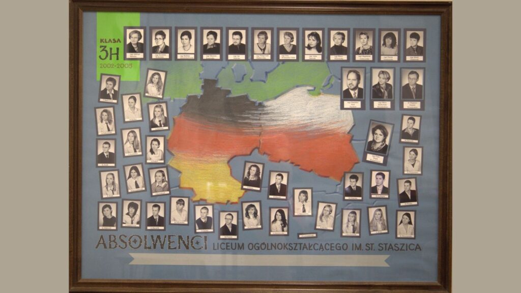 Tło w kolorze niebieskim z dużym, kolorowym szkicem mapy Niemiec i Polski, pokrytej pasami kolorów flag: czarnego, czerwonego, żółtego i szarego – nawiązanie do tematyki klasy językowej. U góry po lewej na zielonym tle napis: „Klasa 3H 2002–2005” Na mapie i wokół niej znajdują się czarno-białe zdjęcia uczniów i nauczycieli w ramkach – niektóre lekko nachylone, tworząc dynamiczny układ. Na dole duży napis: „ABSOLWENCI Liceum Ogólnokształcącego im. St. Staszica”.