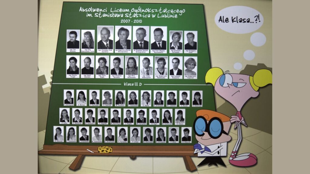 Opis ogólny: Tablica w formie zielonej, ukośnej tablicy szkolnej osadzonej na drewnianych nogach. Po prawej stronie widoczne są postacie z kreskówki „Laboratorium Dextera” – Dexter i Dee Dee. Dee Dee ma chmurkę z napisem: „Ale klasa…?!”. Układ: Górny rząd: portrety nauczycieli i wychowawcy w czarno-białych prostokątach z nazwiskami. Poniżej, dwa poziome rzędy uczniów klasy III D – łącznie 35 portretów. Wszystkie zdjęcia utrzymane w jednakowym stylu – twarze na jasnym tle, podpisywane pełnym imieniem i nazwiskiem lub inicjałem.