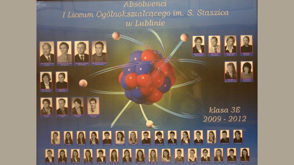 Opis tła: Tło w tonacji niebiesko-zielonej. W centralnym miejscu znajduje się realistyczna wizualizacja modelu atomu: czerwono-niebieskie jądro otoczone orbitującymi elektronami – cienkie, jasne okręgi z małymi kulkami. Układ zdjęć: Górna część: dyrekcja i nauczyciele – zdjęcia czarno-białe, oprawione w fioletowe ramki. Dolna część: uczniowie – dwa rzędy portretów, każdy podpisany. Zdjęcia uczniów kolorowe, jednolite tło.