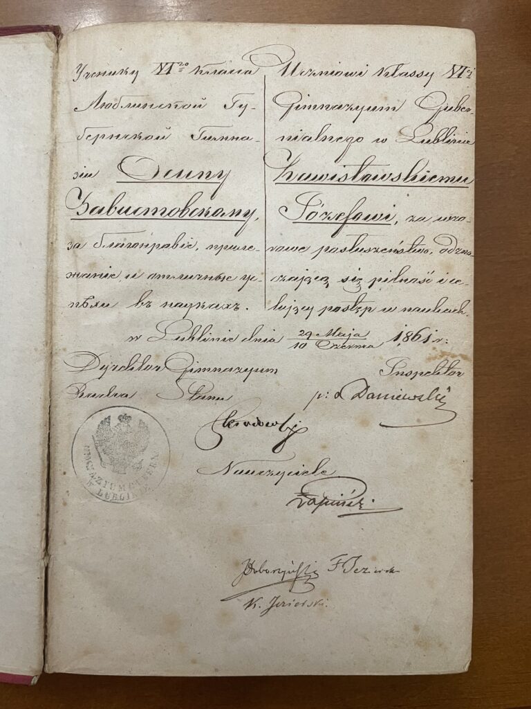 Ostatnie zdjęcie przedstawia kolejną stronę dokumentu w podobnym stylu – ozdobne, starannie wykaligrafowane pismo w języku rosyjskim.
W treści pojawia się nazwisko Zabłotnowskiemu Józefowi, a także data 29 maja (10 czerwca) 1865 roku – zapis zgodny z kalendarzem juliańskim i gregoriańskim.
Na dole widoczny jest odcisk okrągłej pieczęci z godłem carskim (dwugłowy orzeł), z napisem w języku rosyjskim „Гимназия в Люблине” (Gimnazjum w Lublinie).
Pod tekstem widnieje kilka podpisów nauczycieli i dyrektora, między innymi Dobrowolski, Florin, Jurkowski.
Strona ma pożółkły papier i delikatne ślady użytkowania, co wskazuje na jej wiek – ponad 150 lat.
