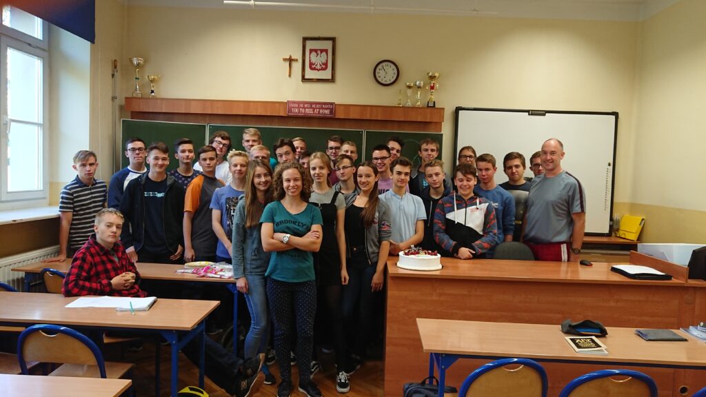 Zdjęcie klasowe w sali – uczniowie + tort (prawdopodobnie urodziny/świętowanie).