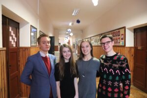 Szkolny korytarz – czwórka uczniów pozuje do zdjęcia.