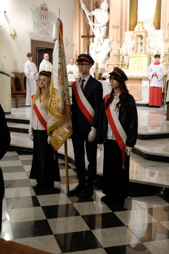 Poczet sztandarowy stoi w kościele podczas uroczystości.