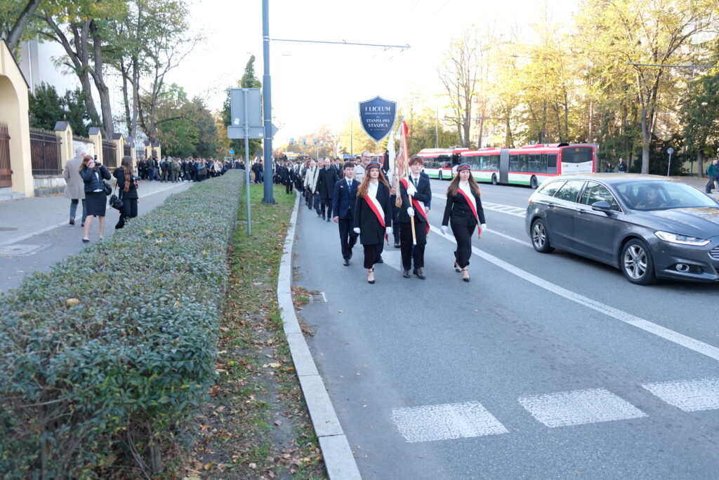 Poczet sztandarowy idzie ulicą podczas uroczystego przemarszu.