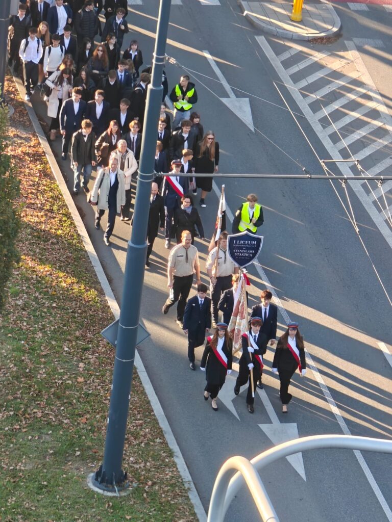 Uczestnicy przemarszu idą ulicą w zorganizowanej grupie.