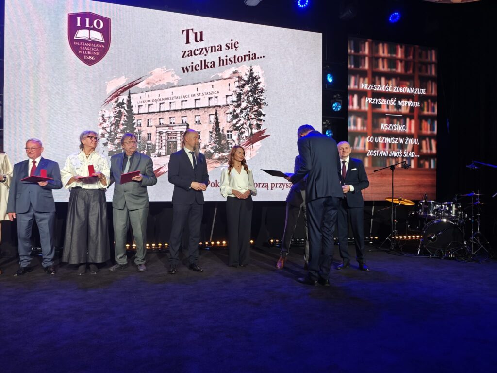 Kilka osób uczestniczy w ceremonii wręczania wyróżnień na scenie.