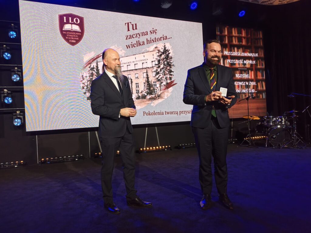 Dwaj mężczyźni stoją na scenie podczas oficjalnej części jubileuszu.