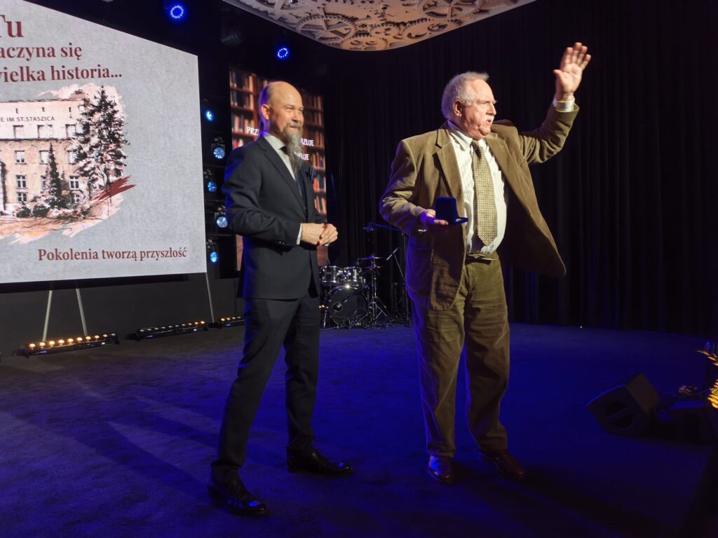 Dwie osoby stoją na scenie podczas oficjalnej części jubileuszu.