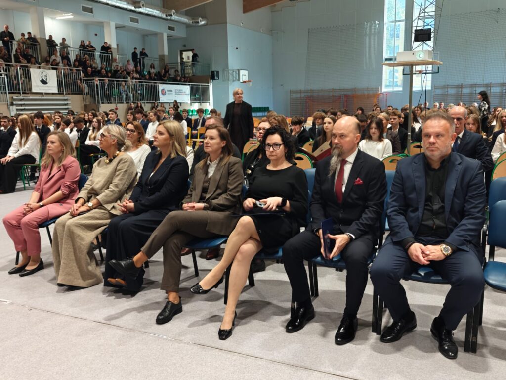 Zaproszeni goście siedzą w pierwszych rzędach podczas uroczystości szkolnej.