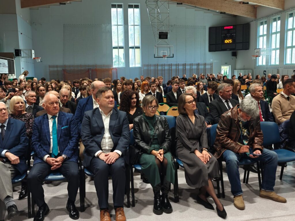 Zaproszeni goście siedzą w pierwszych rzędach sali gimnastycznej.