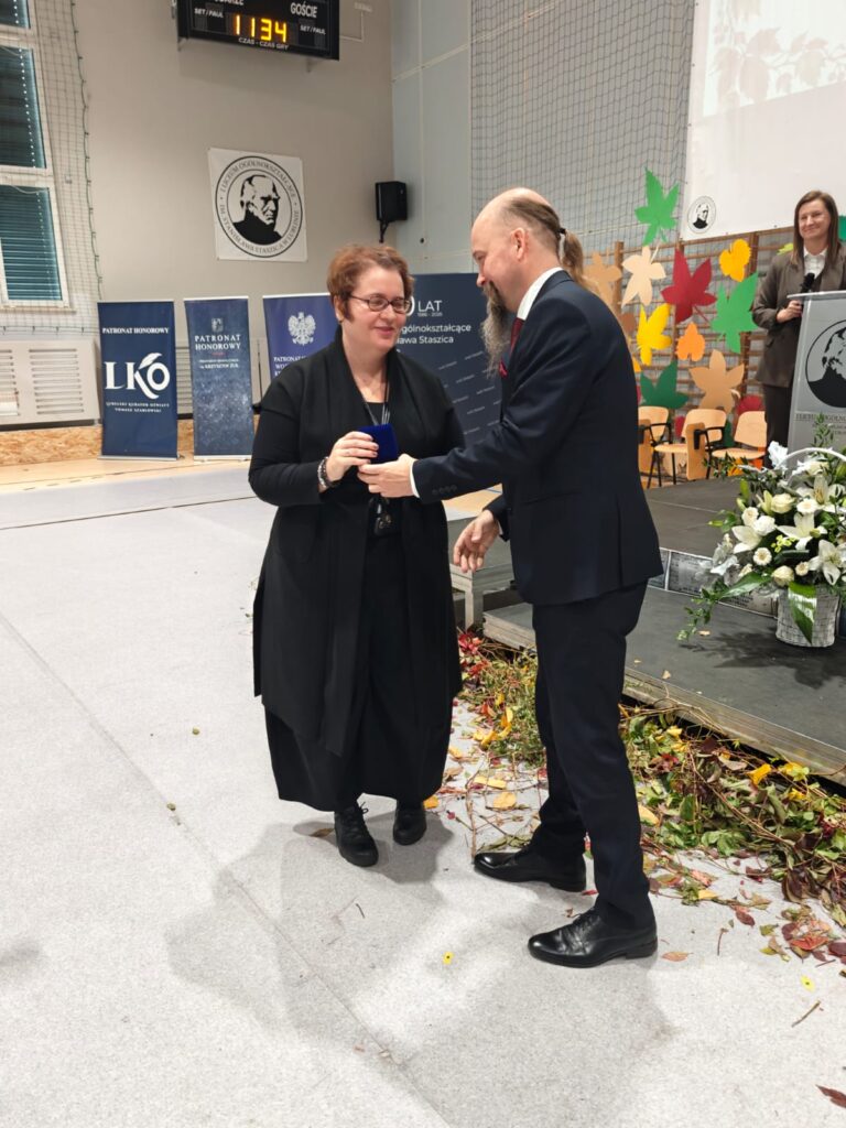 Mężczyzna przekazuje drobny upominek kobiecie ubranej na czarno.