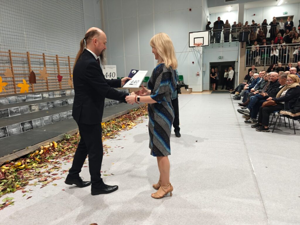 Mężczyzna przekazuje dokument kobiecie w długiej sukni.