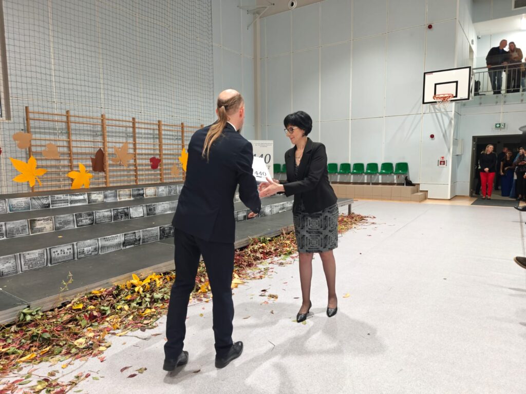 Mężczyzna gratuluje kobiecie podczas ceremonii wręczania wyróżnień.